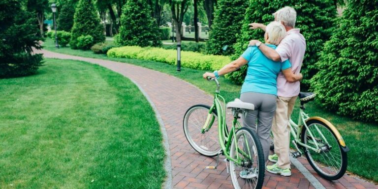 Elderly Couple in a Sweet Gesture While Walking Along Themed Garden Path At Memory Care Facility